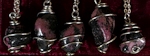 Rhodonite tumbled stones wire wrapped into pendants on necklaces. Rhodonite is an opaque pink stone with black streaks of Manganese